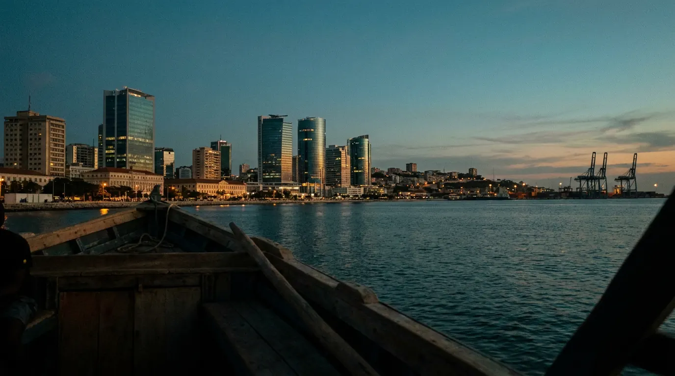 Luanda bay skyline at dusk seen from the water, glass towers along the Marginal with port cranes at the far edge — documentary placeholder